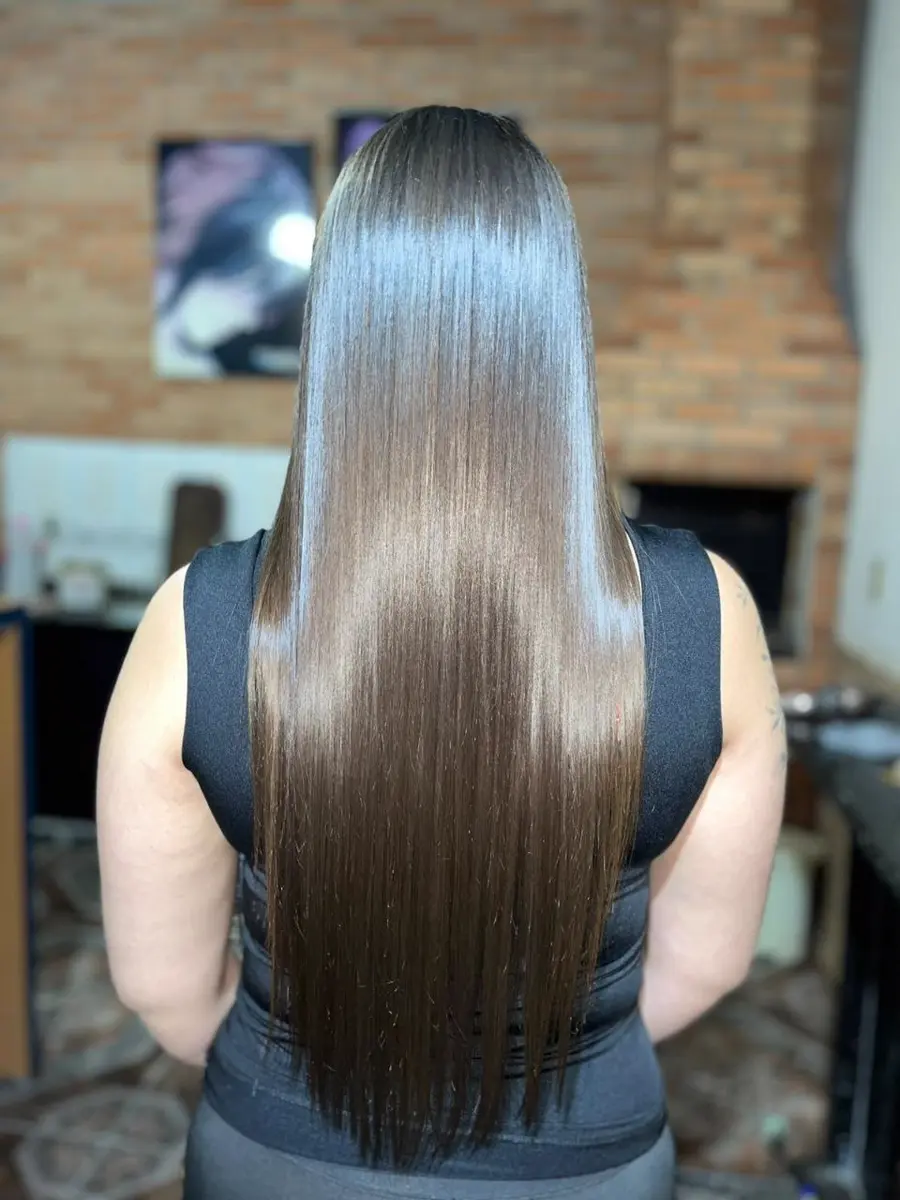 Cliente com cabelo liso e brilhante após procedimento químico, mostrando fios cuidados e alinhados